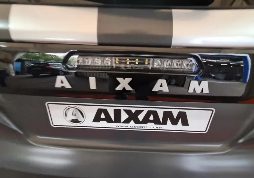 Gros plan sur la calandre avant grise claire de l'Aixam Ambition 2024 avec logo et feu LED intégré.