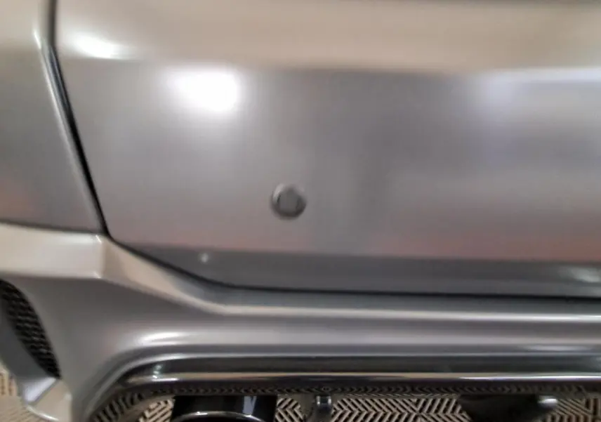 Gros plan sur le pare-chocs arrière gris clair de l'AIXAM AMBITION 2024 avec capteur de recul intégré.