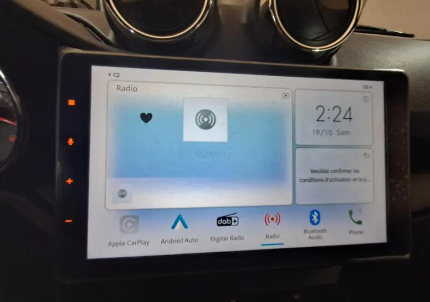 Écran tactile central de l’Aixam Ambition gris clair, affichant les options radio et connectivité, vue de face rapprochée.