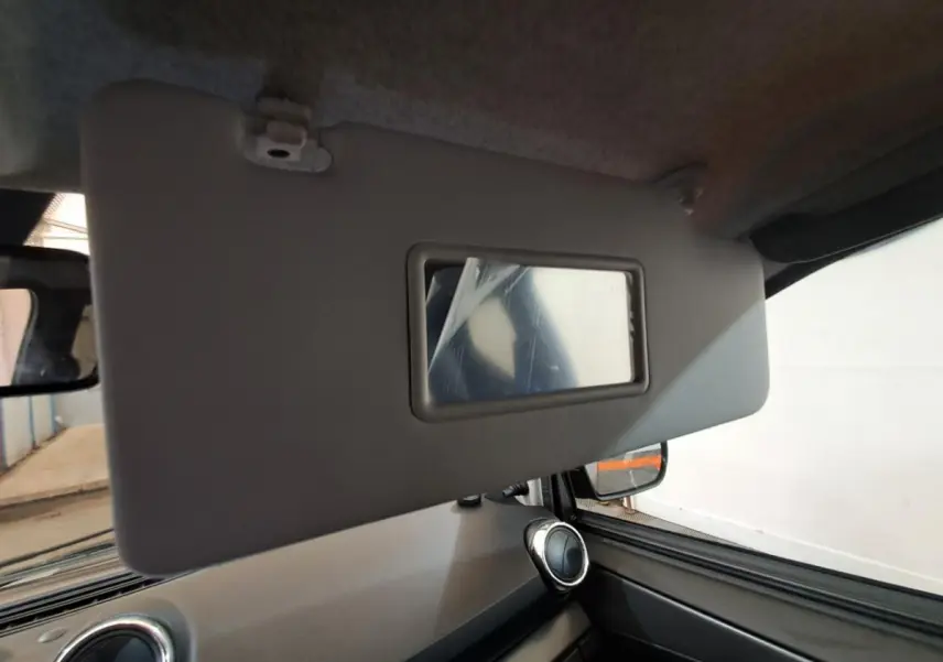 Détail du pare-soleil côté conducteur avec miroir intégré dans l’habitacle gris de l’Aixam Ambition 2024.