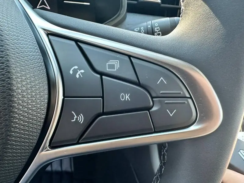 Gros plan sur les commandes multifonctions noires du volant côté droit de la Renault Clio Gris Rafale 2025.