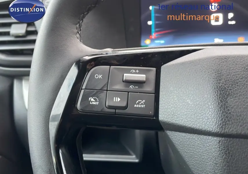 Gros plan sur les commandes au volant en cuir noir du Citroën Jumpy L3 gris titane, avec affichage numérique en arrière-plan.
