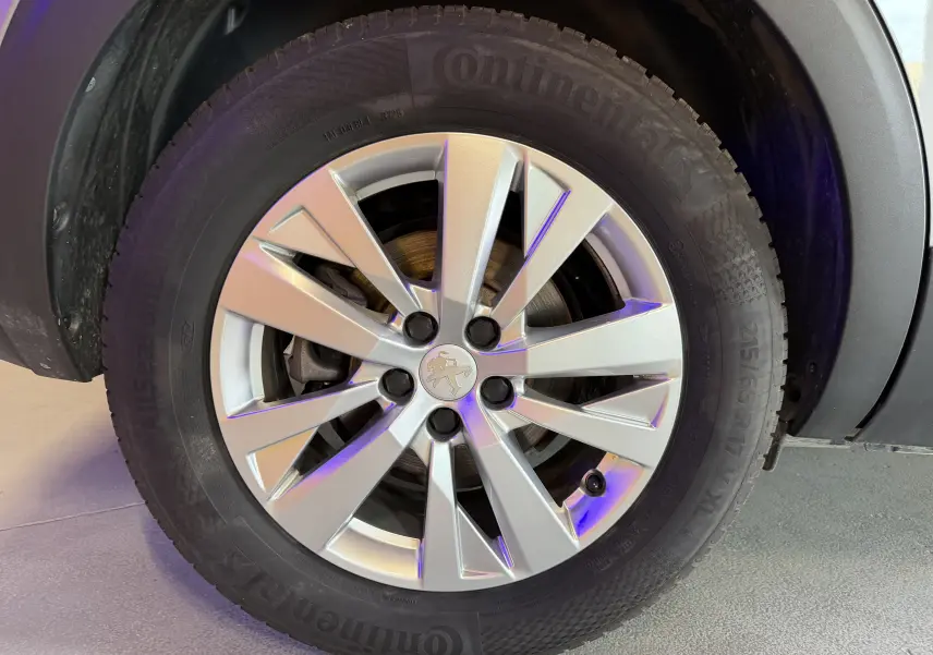 Gros plan sur la roue avant droite du Peugeot 5008 gris 2021, avec jante argentée et logo lion au centre.