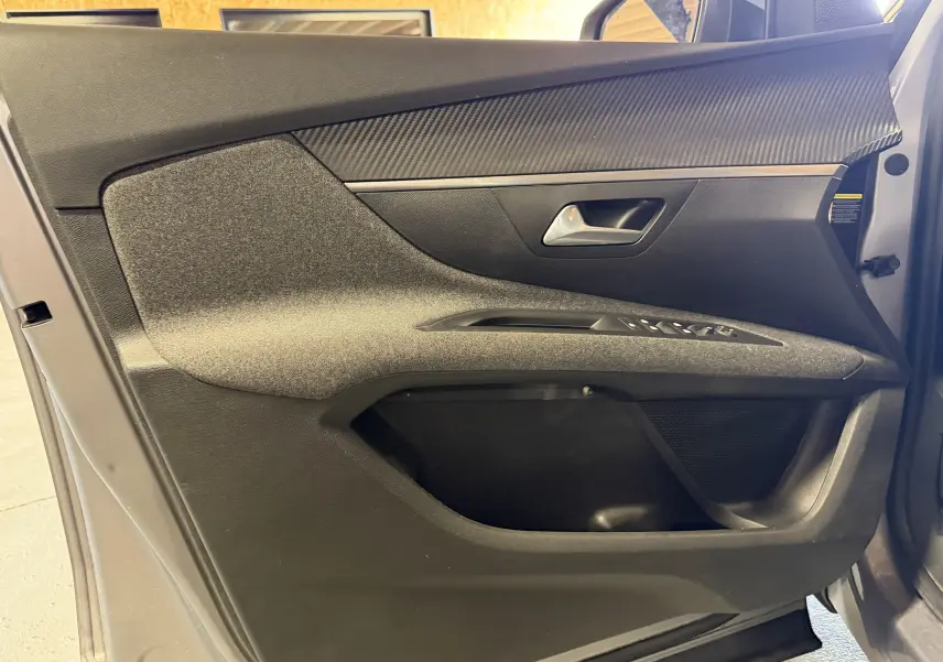 Vue rapprochée de la porte avant gauche grise du Peugeot 5008 1.5 BlueHDi, avec garniture noire et commandes de vitres.