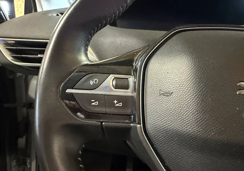 Gros plan sur le volant noir du Peugeot 5008 1.5 BlueHDi 130, avec commandes audio intégrées à gauche.
