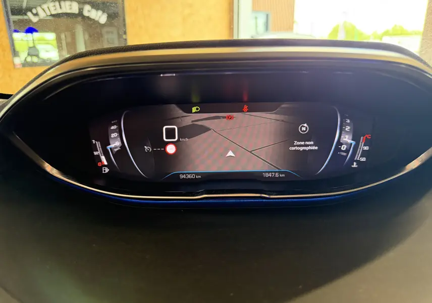 Vue rapprochée du tableau de bord numérique du Peugeot 5008 gris, affichant la navigation et les indicateurs de vitesse et température.