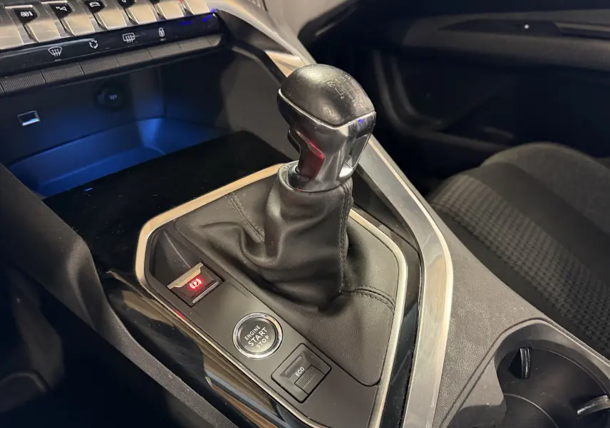 Gros plan sur le levier de vitesses manuel noir et la console centrale du Peugeot 5008 gris, avec bouton start/stop et frein à main électrique.