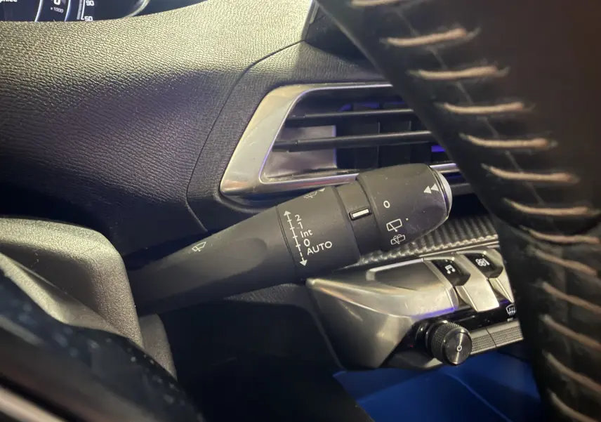 Gros plan sur la commande d’essuie-glace côté gauche du tableau de bord noir du Peugeot 5008 gris 2021.