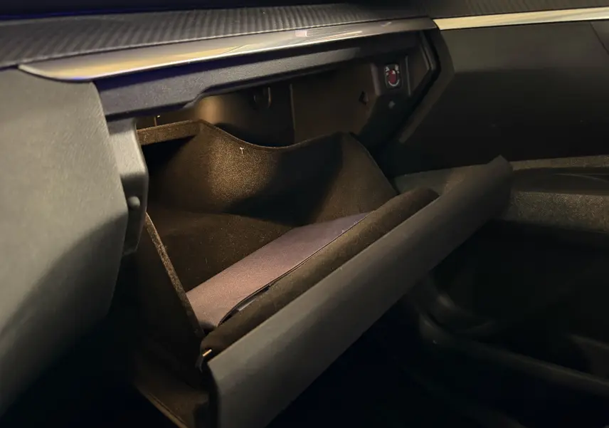 Vue intérieure du coffre à gants ouvert du Peugeot 5008 gris, mettant en valeur son espace de rangement doublé de tissu noir.
