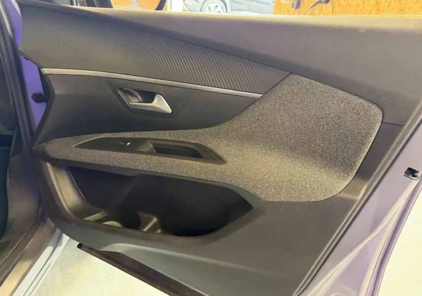 Gros plan sur la garniture intérieure de la porte arrière gauche du Peugeot 5008 gris, avec insert tissu et poignée argentée.