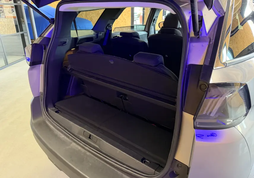 Coffre ouvert vu de l'arrière droit d'un Peugeot 5008 gris 2021, montrant la banquette arrière et l'intérieur noir.