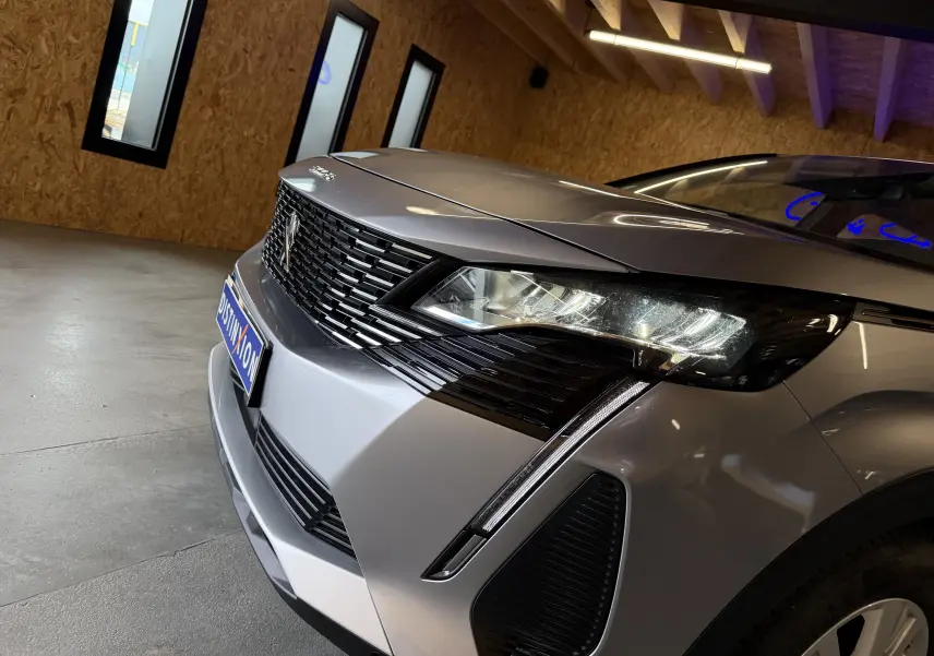 Vue 3/4 avant droit du Peugeot 5008 gris 2021, mettant en valeur la calandre noire et les phares LED distinctifs.