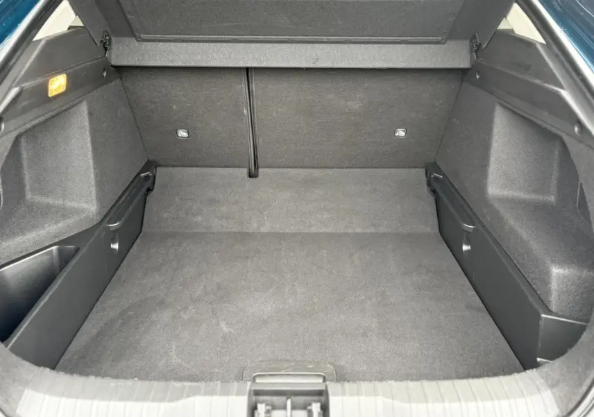 Coffre spacieux et vide de la Renault Arkana TCE 140 bleu Zanzibar, vue intérieure arrière avec habillage noir.