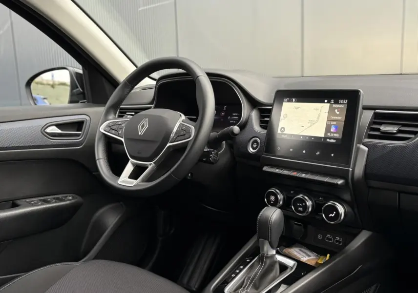 Vue intérieure côté conducteur de la Renault Arkana TCE 140 avec tableau de bord numérique et écran tactile GPS.