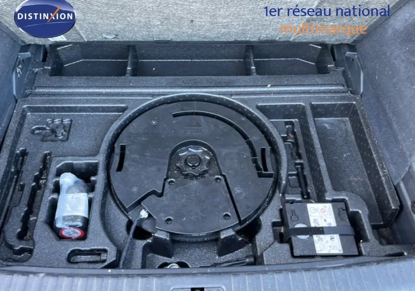 Coffre ouvert montrant le rangement sous plancher avec kit de réparation et emplacement roue de secours du Audi Q3 Sportback noir.