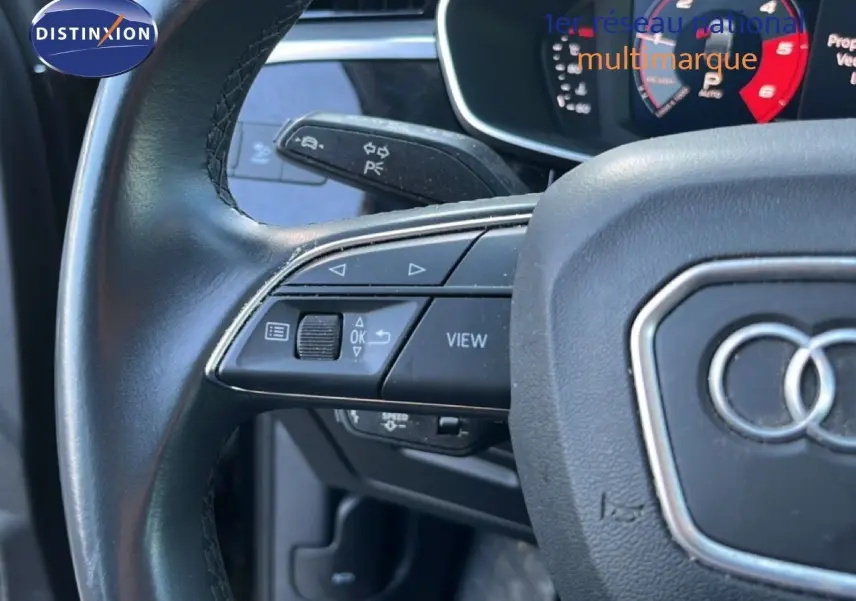 Gros plan sur le volant noir d’un Audi Q3 Sportback 2022, montrant les commandes multifonctions côté gauche et le logo Audi central.