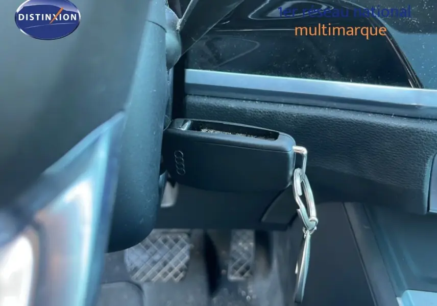 Gros plan sur la clé Audi accrochée sous le volant, avec vue partielle du tableau de bord noir intérieur du Q3 Sportback.