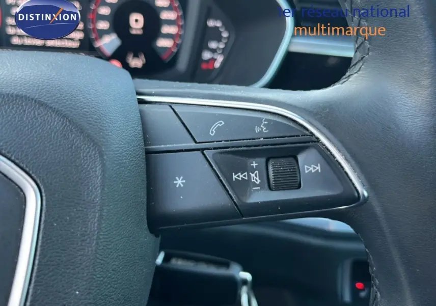 Gros plan sur les commandes au volant à droite de l'Audi Q3 Sportback noir, avec tableau de bord numérique en arrière-plan flou.