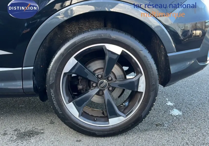 Gros plan sur la roue avant droite noire d’un Audi Q3 Sportback 35 TDI 150 S-Line 2022 avec jante alliage bicolore.