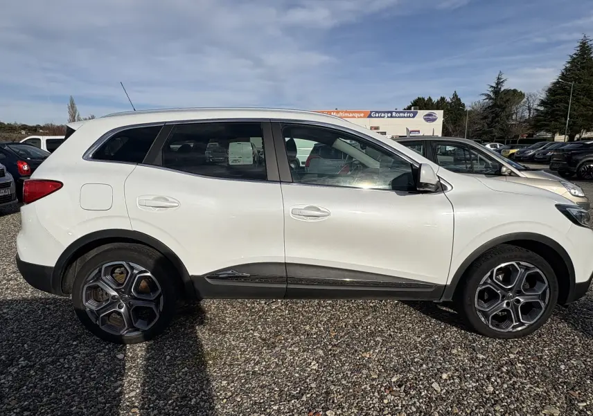 Profil côté gauche d’un Renault Kadjar blanc de 2015 avec jantes alliage et détails noirs sur les bas de caisse.