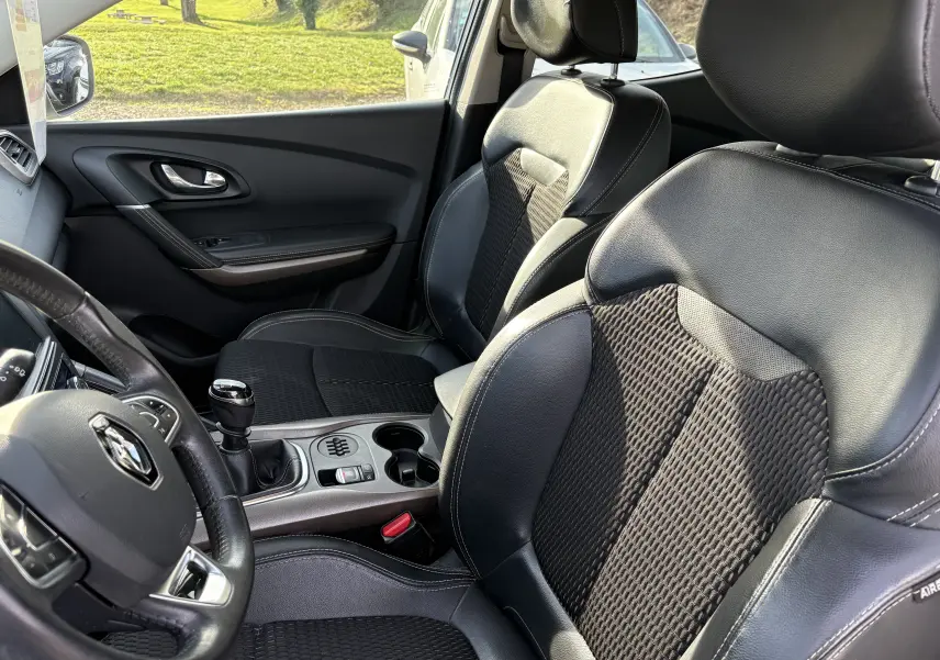 Intérieur du Renault Kadjar 2015, vue côté conducteur, sièges noirs en cuir et tissu avec levier de vitesses manuel visible.
