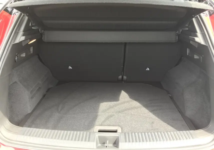 Coffre ouvert vu de l'arrière du Renault Austral rouge et noir, montrant l'espace de chargement vide et la moquette grise.