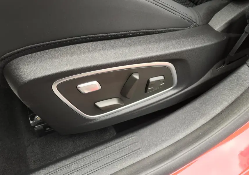 Gros plan sur les commandes de réglage électrique du siège conducteur noir du Renault Austral rouge et noir, côté gauche.