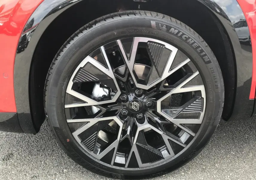 Gros plan sur la jante alliage 20 pouces noire et diamantée du côté avant gauche du Renault Austral rouge et noir.