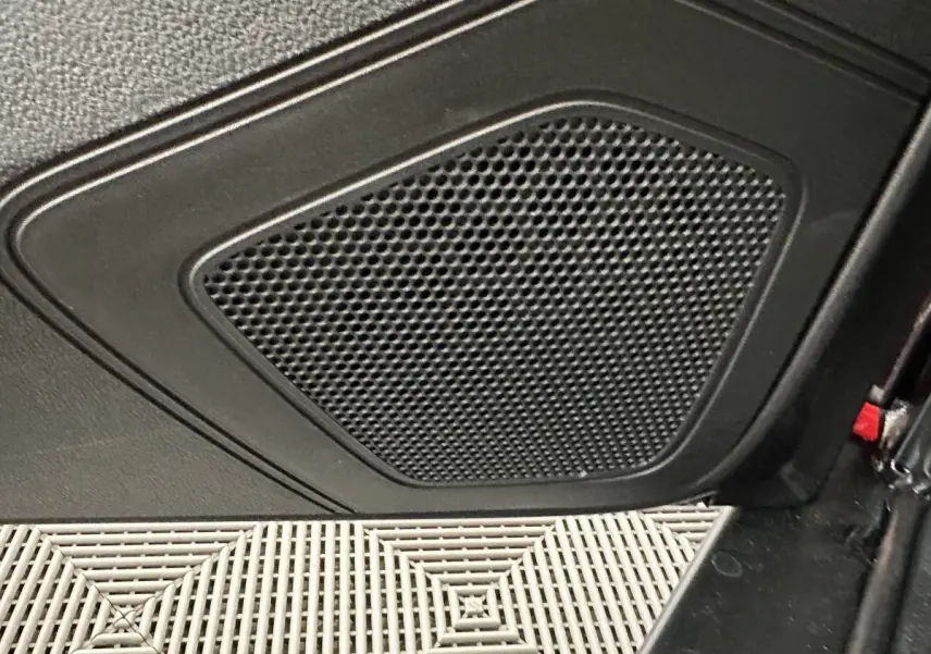 Gros plan sur la grille de haut-parleur noir intégrée à la porte intérieure d'une Aixam Ambition E City Pack rouge.