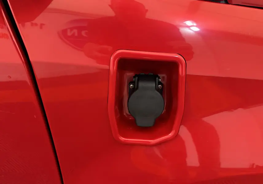 Prise de recharge électrique en gros plan sur le côté gauche rouge de l'AIXAM AMBITION E CITY PACK 2026.
