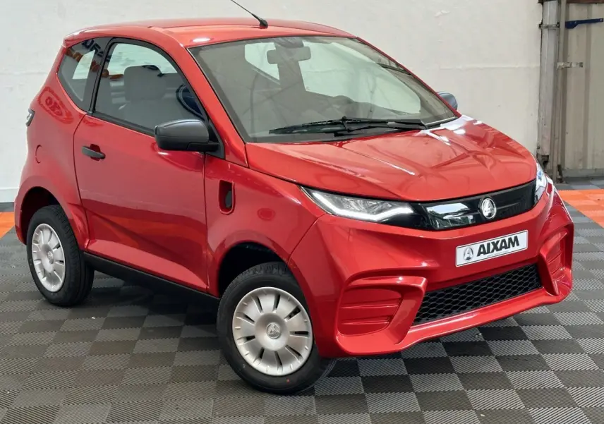 Vue 3/4 avant droite de l'AIXAM AMBITION E CITY PACK rouge 2026 avec rétroviseur caméra côté conducteur.