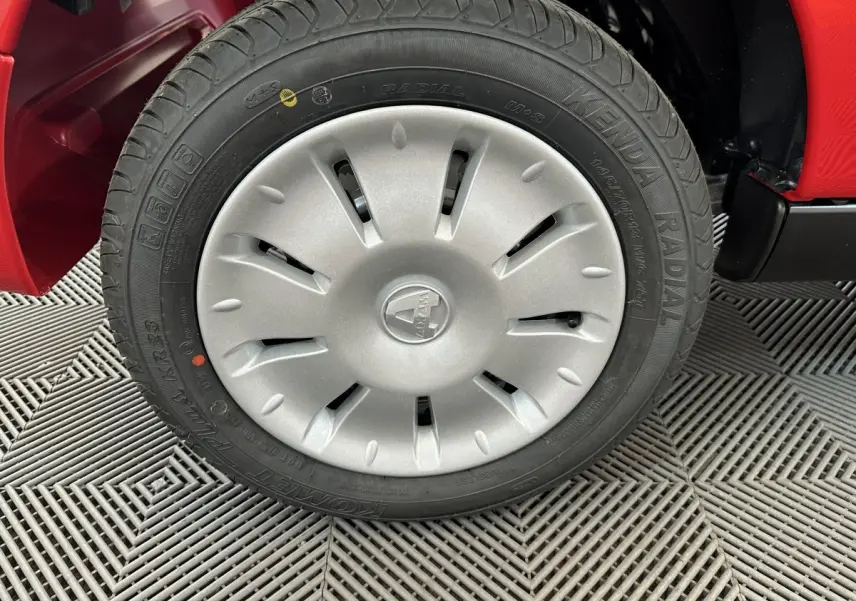 Gros plan sur la roue avant gauche d'une Aixam Ambition E City Pack rouge, mettant en valeur la jante et le pneu radial.