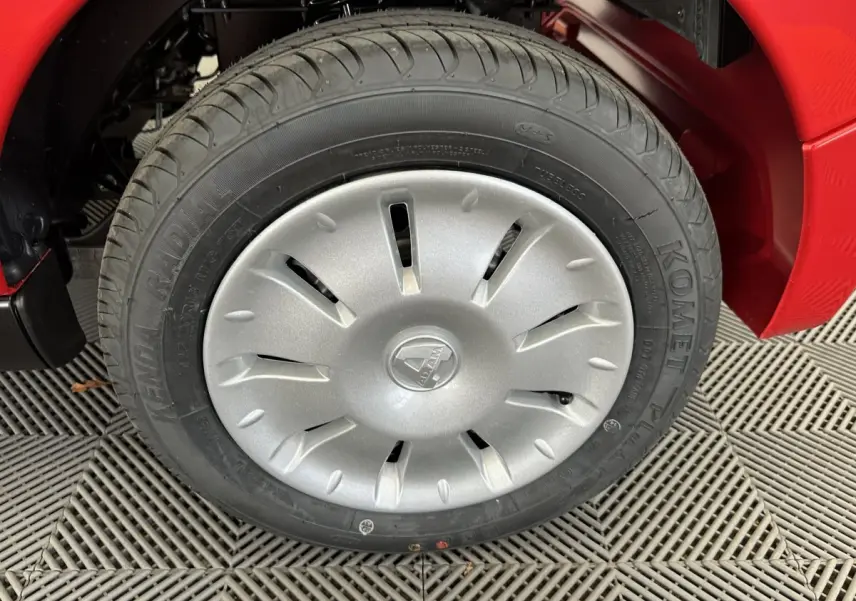 Gros plan sur la roue avant gauche d'une Aixam Ambition E City Pack rouge avec enjoliveur argenté et logo central.