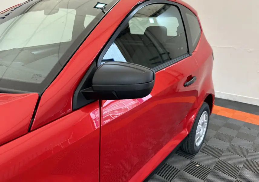 Vue de côté droit rapprochée sur l'AIXAM AMBITION E CITY PACK rouge avec rétroviseur caméra côté conducteur visible.