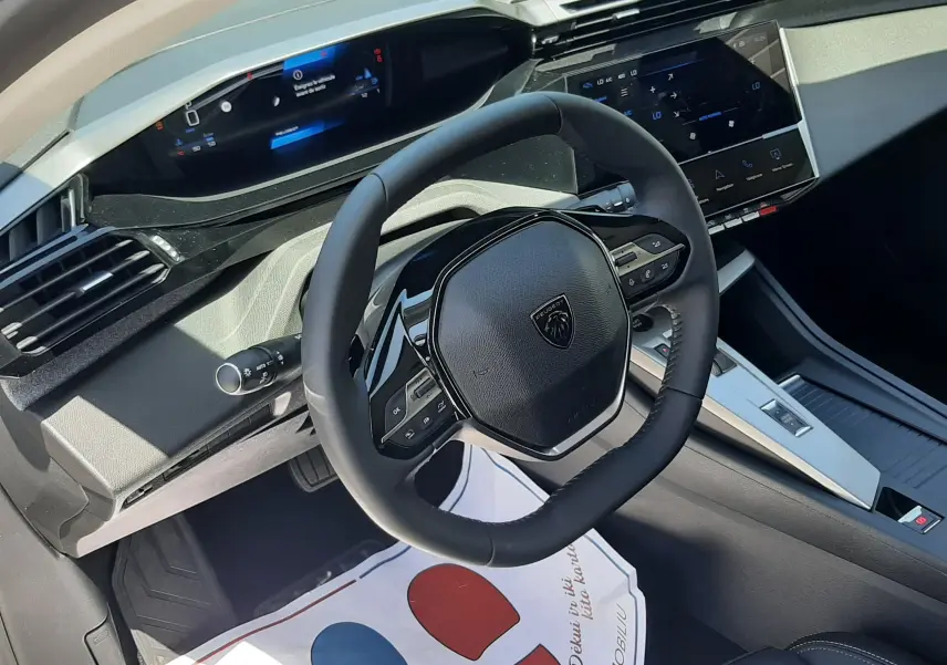 Vue intérieure côté conducteur du tableau de bord et volant noir de la Peugeot 308 gris selenium, avec écran tactile et instrumentation digitale.