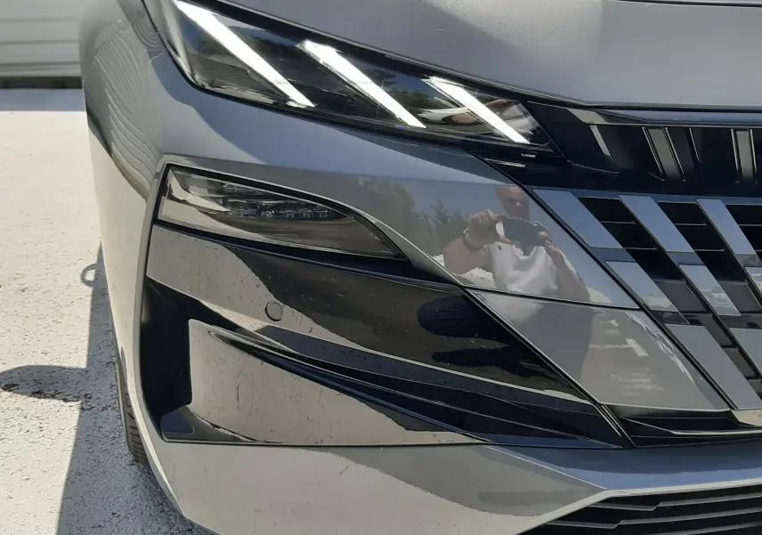Gros plan sur l'avant droit gris selenium du Peugeot 308 III Ph.2 avec ses phares LED distinctifs et la calandre noire brillante.