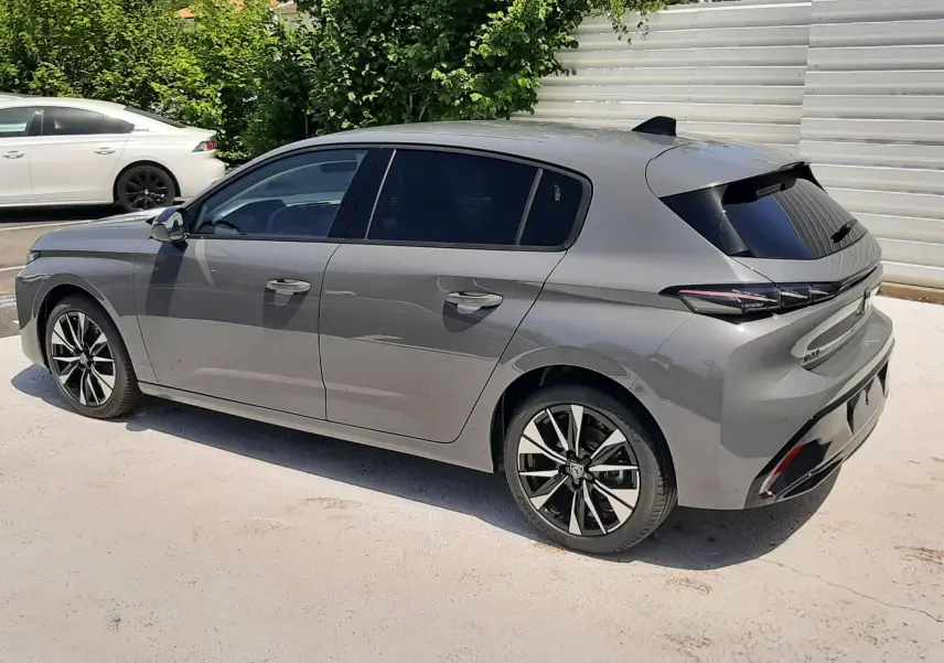 Peugeot 308 gris sélénium vue 3/4 arrière côté droit, avec jantes alliage et vitres teintées.