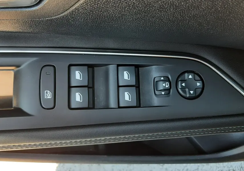 Gros plan sur la commande des vitres électriques côté conducteur du Peugeot 3008 gris platinium, avec boutons noirs et surpiqûres blanches.