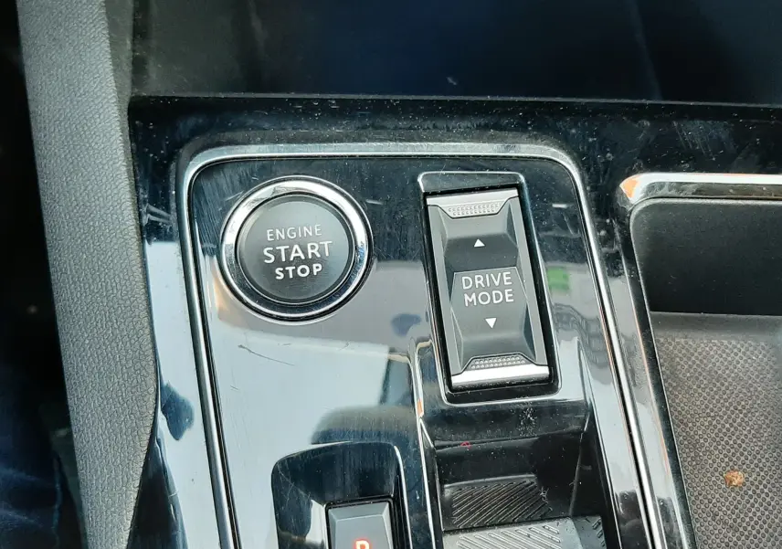 Gros plan sur la console centrale noire brillante du Peugeot 3008 2023, avec bouton start/stop et sélecteur drive mode.