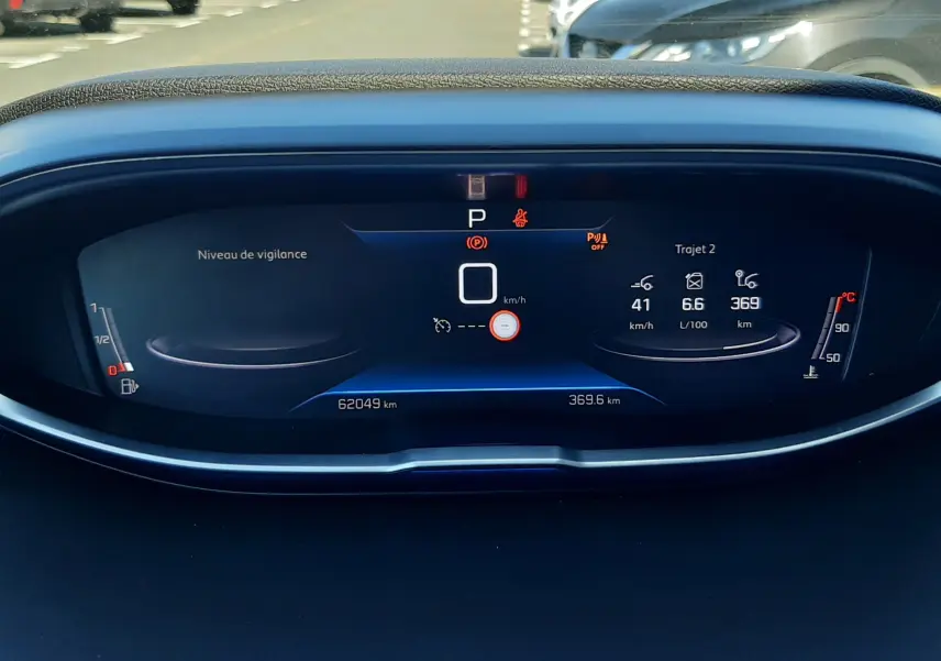 Tableau de bord numérique du Peugeot 3008 gris platinium, affichant la vitesse, la consommation et le niveau de vigilance.