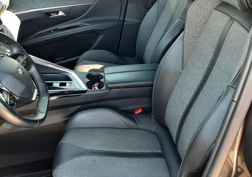 Vue intérieure côté conducteur du Peugeot 3008 2023, sièges gris tissu et cuir avec console centrale noire.