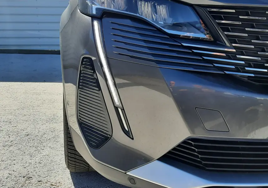 Gros plan sur l'avant gauche du Peugeot 3008 gris platinium, mettant en valeur le phare LED et la calandre distinctive.