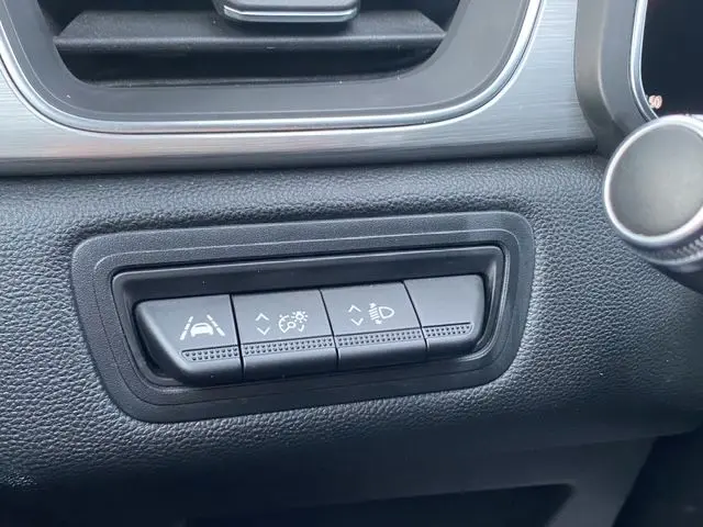 Gros plan sur les boutons de réglage d'assistance à la conduite et des phares dans l'habitacle noir du Renault Captur blanc nacré 2021.