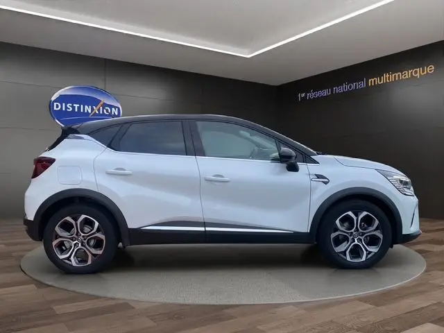Vue de profil côté gauche du Renault Captur blanc nacré avec toit noir, roues alliage bi-ton et détails noirs contrastants.