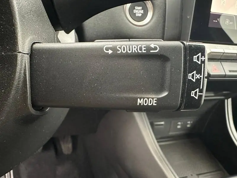 Gros plan sur la commande au volant droite du Renault Captur 2025, avec boutons source et mode visibles, intérieur noir.
