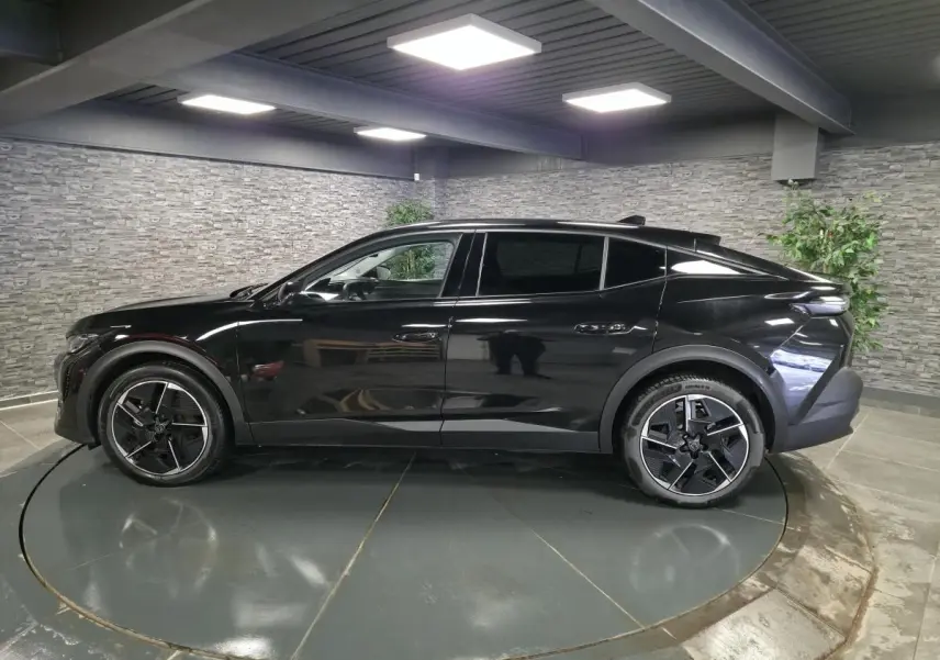 Profil côté gauche d'une Peugeot 408 électrique 2024 noire Perla Nera avec jantes alliage 19 pouces diamantées.