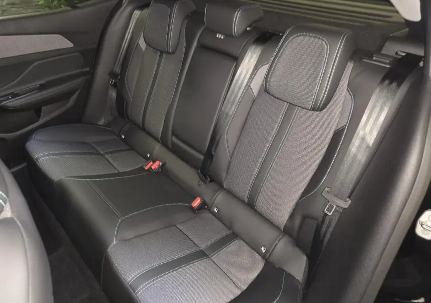 Vue intérieure sur la banquette arrière du Peugeot 408 2024, sellerie tri-matières noire avec surpiqûres bleues.