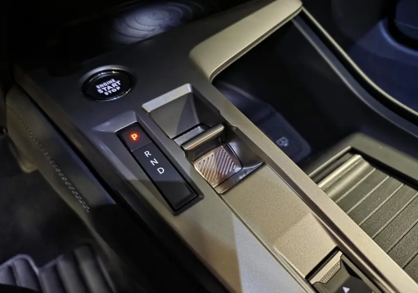 Gros plan sur la console centrale de la Peugeot 408 électrique 2024, montrant la commande de boîte auto et le bouton start/stop.