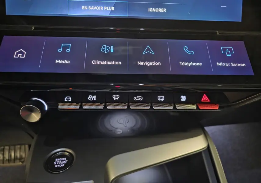 Vue rapprochée de la console centrale tactile et des commandes du Peugeot 408 électrique noir, avec recharge sans fil visible.