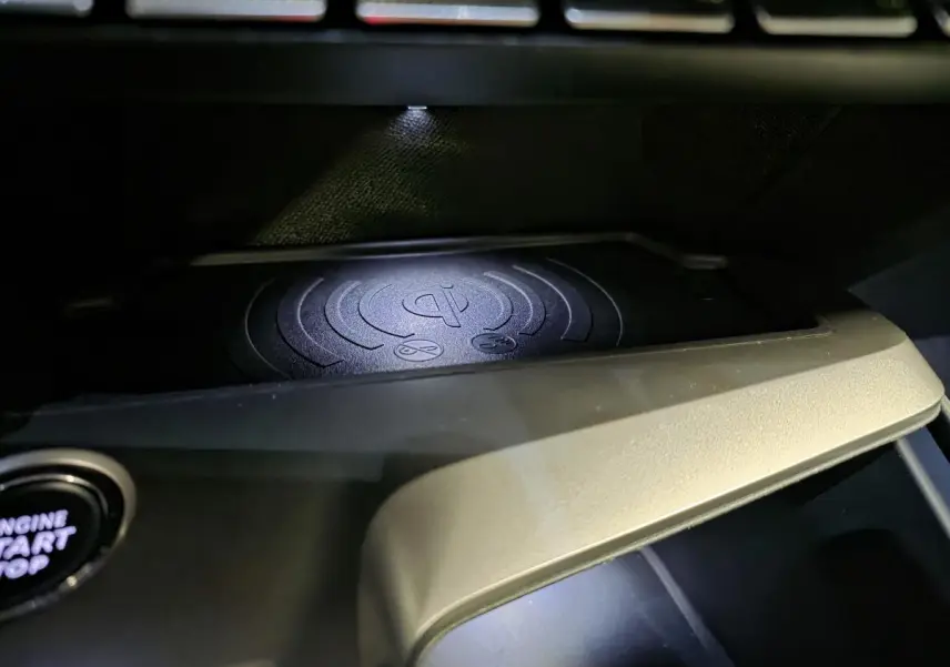 Gros plan sur le chargeur smartphone sans fil Qi dans l'habitacle du Peugeot 408 noir électrique 2024.